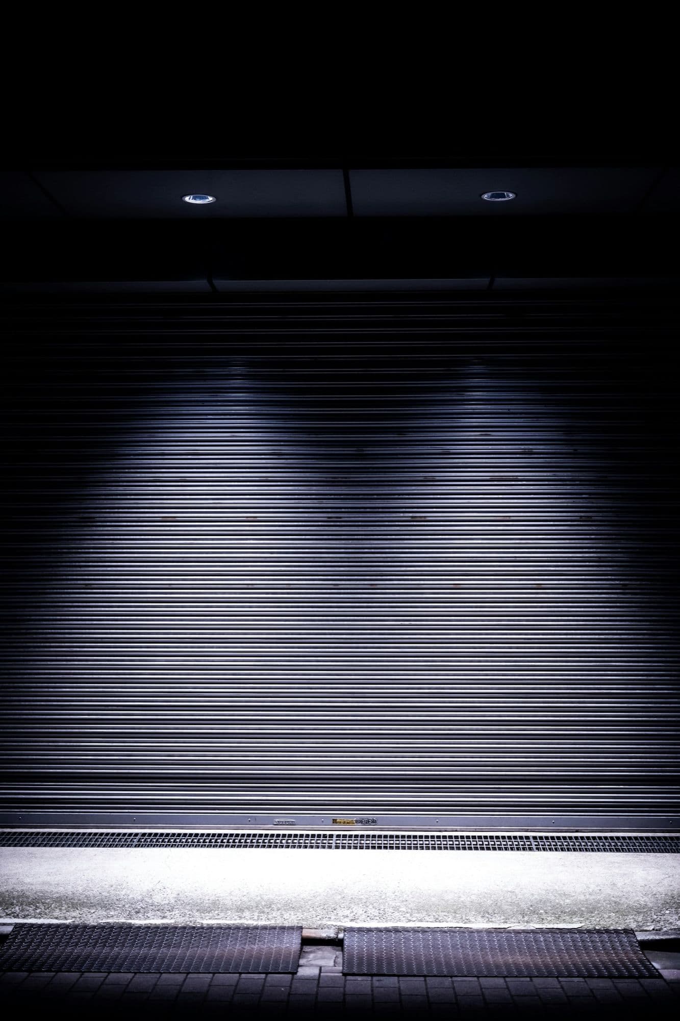A closed roller shutter lit from above at night