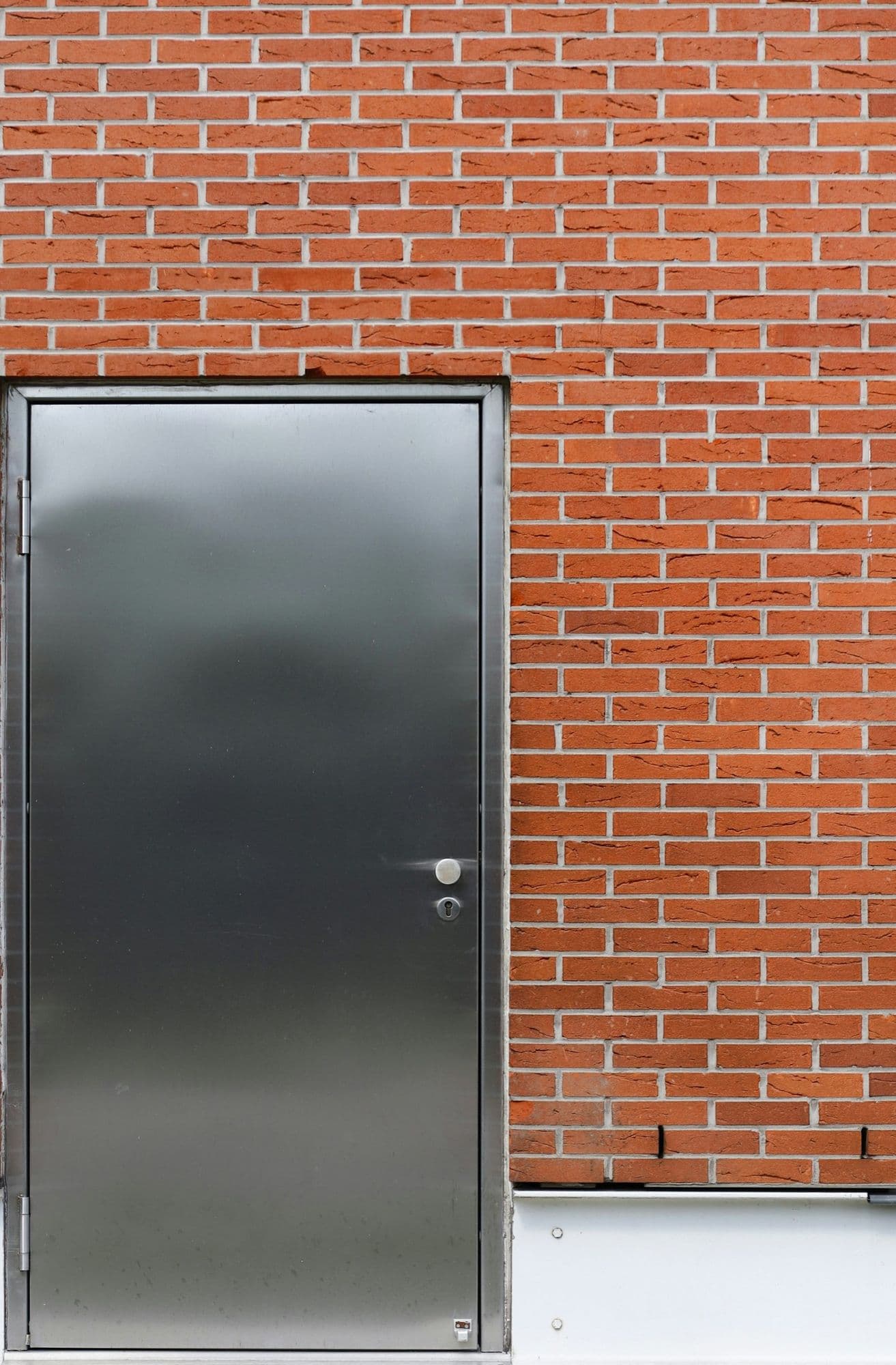 A stainless steel door set into a red brick wall