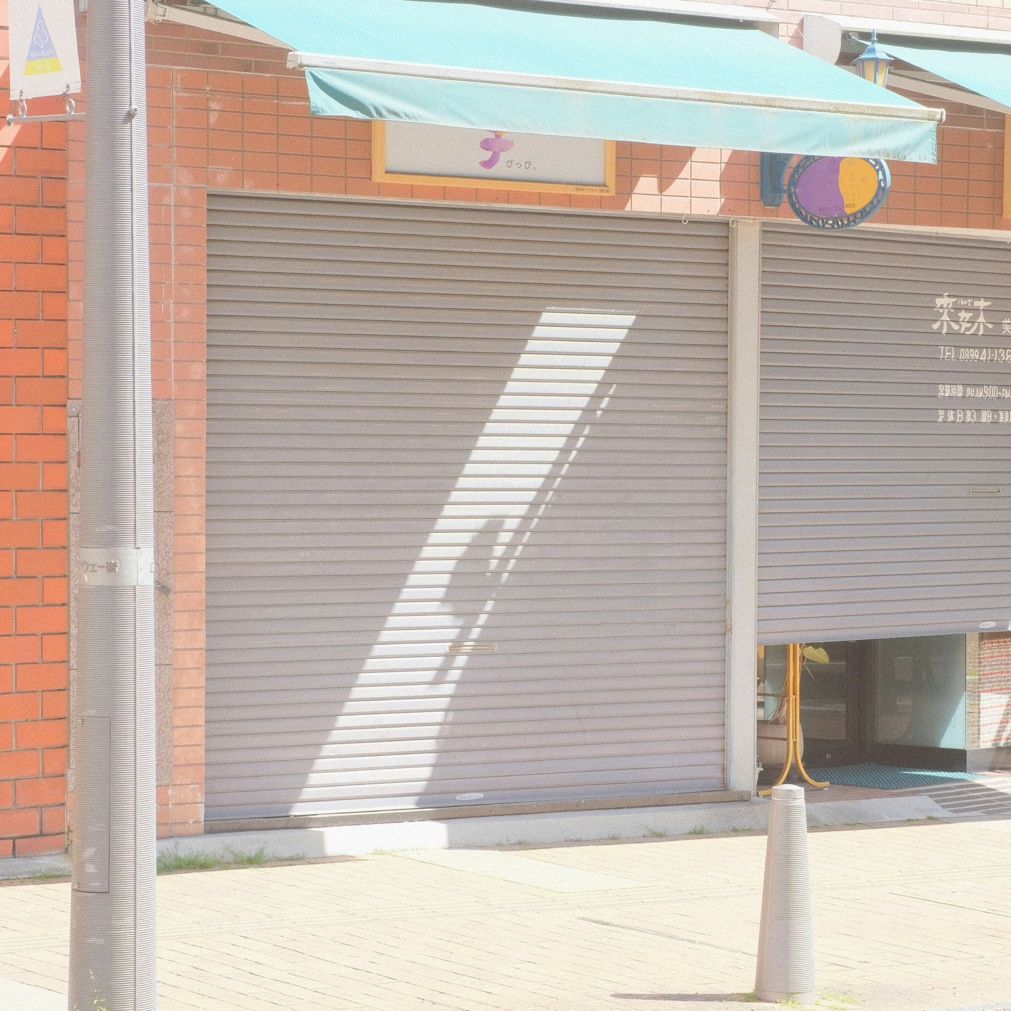 Roller shutters closed beneath a shop awning in daylight